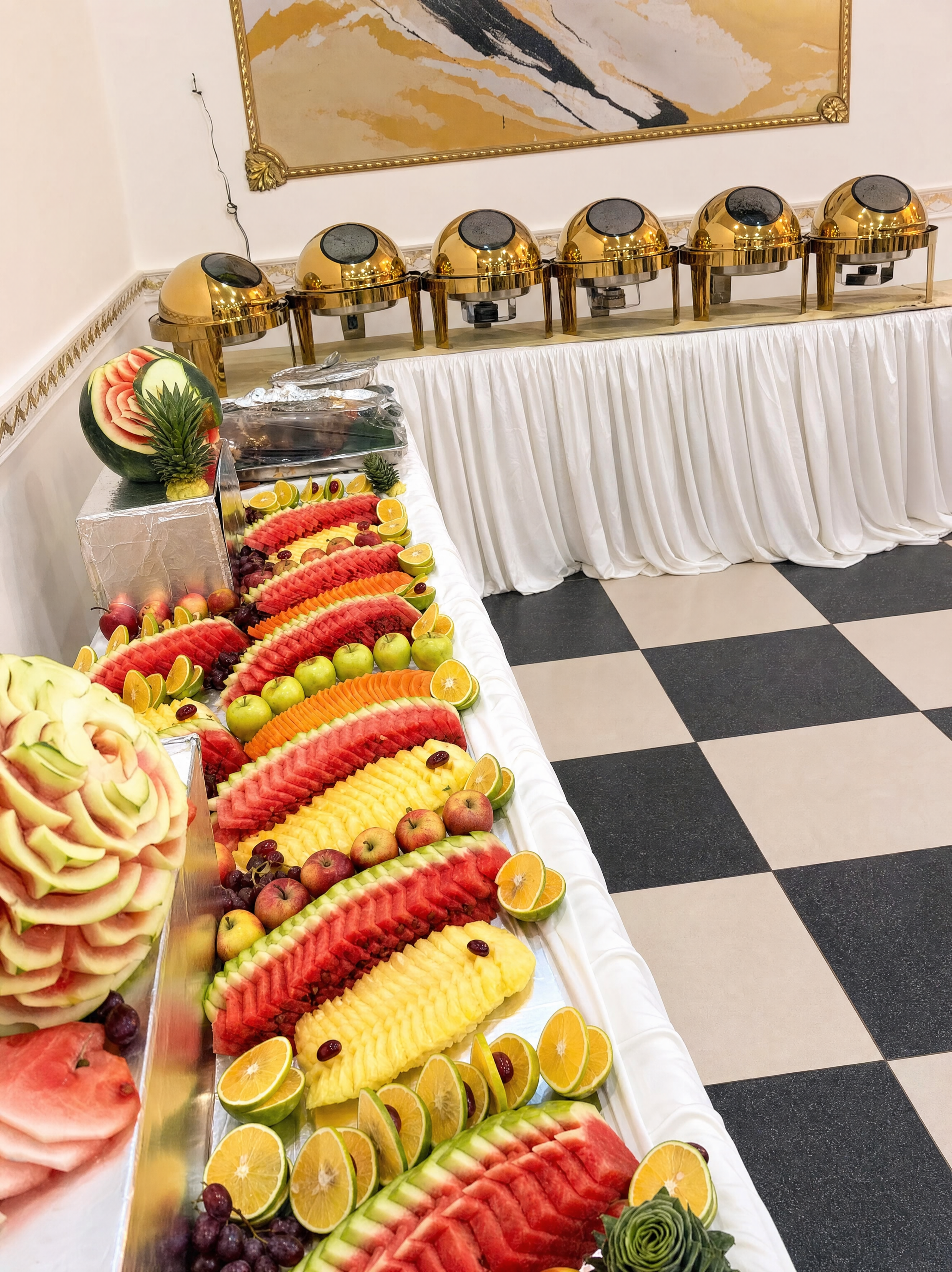 Buffet dressé avec chafing dishes dorés et présentation de fruits sculptés